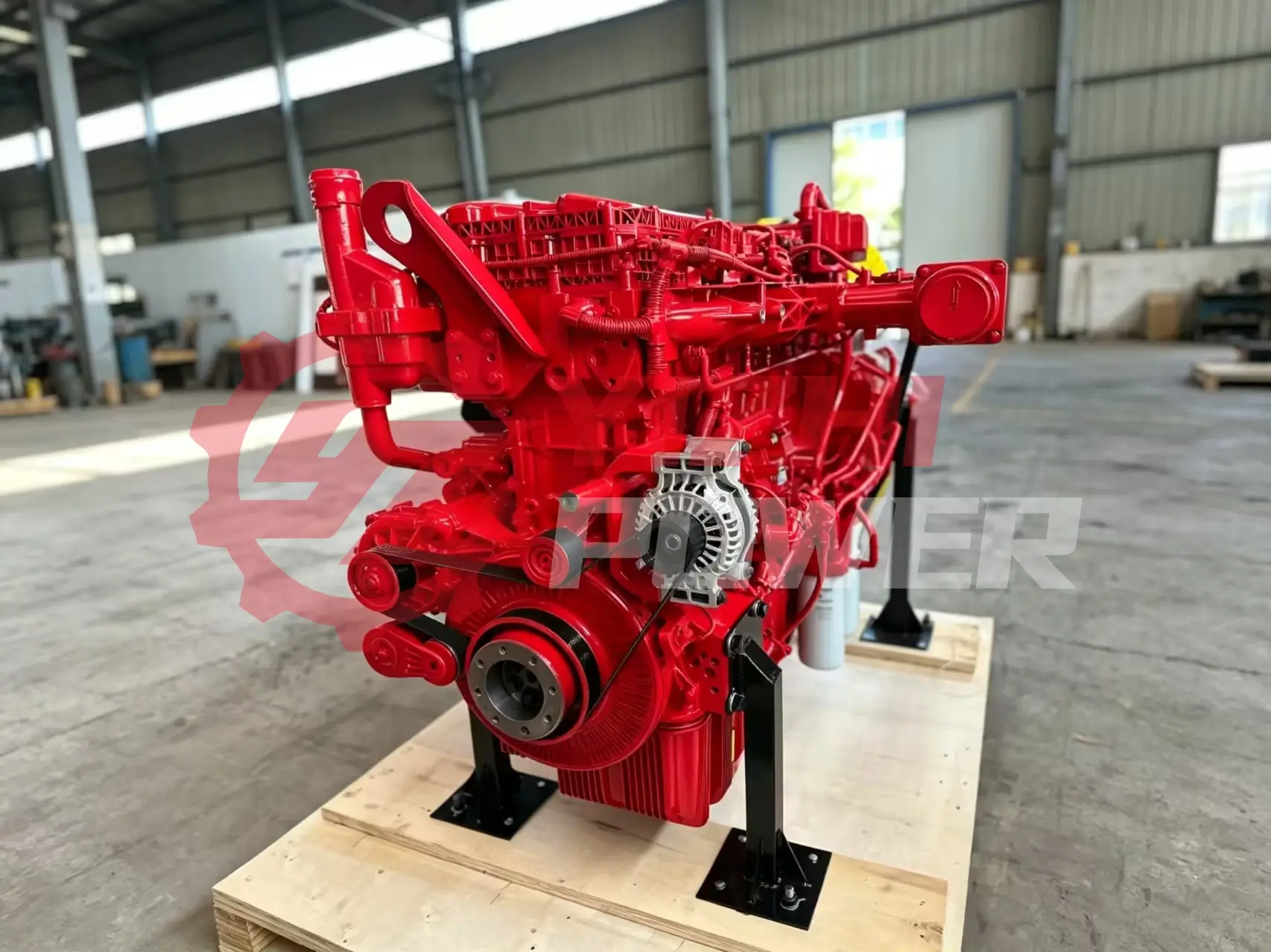 Bright red industrial diesel engine mounted on a stand in a warehouse workshop setting.