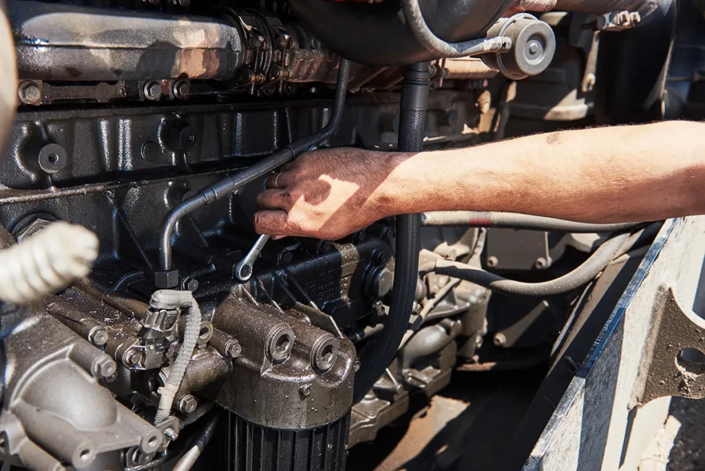technician performing cummins engine maintenance inspection on heavy-duty diesel engine components