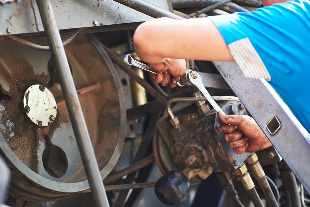 technician performing cummins engine maintenance on heavy-duty diesel engine using repair tools