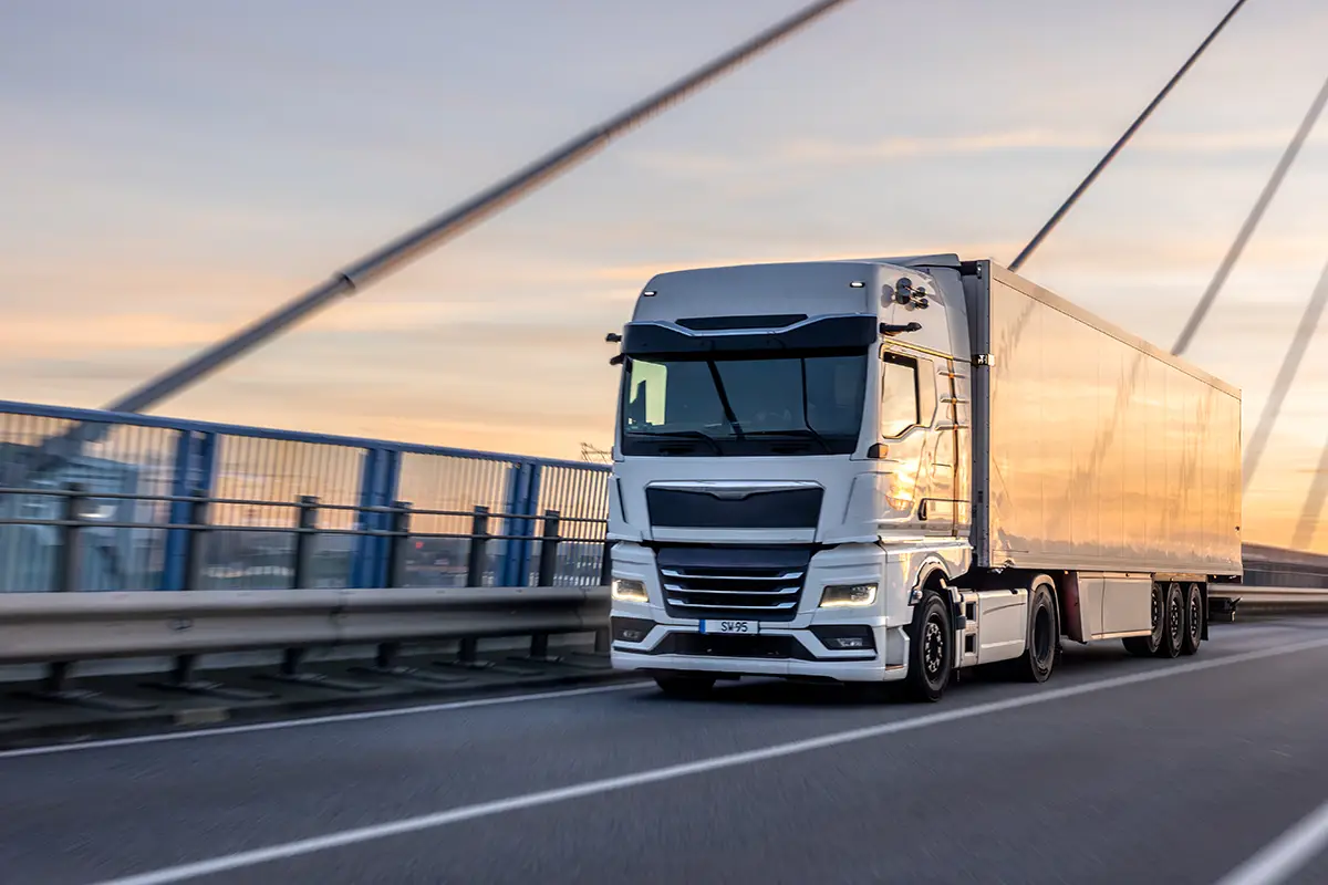 long haul truck engines powering truck on highway bridge at sunset