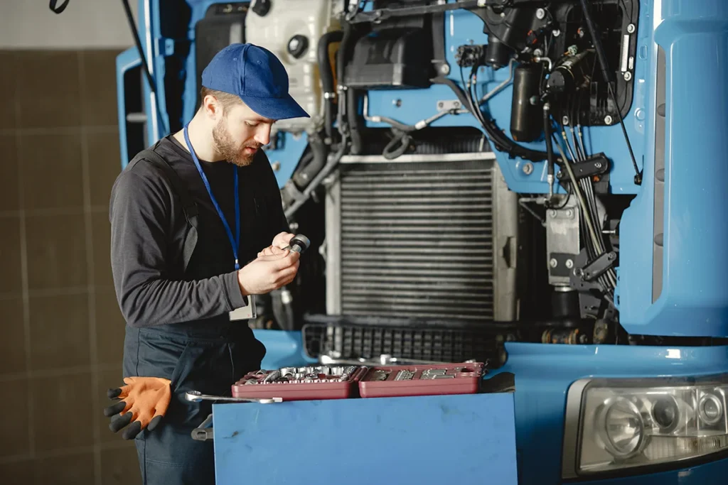 technician performing diesel engine troubleshooting on heavy duty truck engine in repair shop